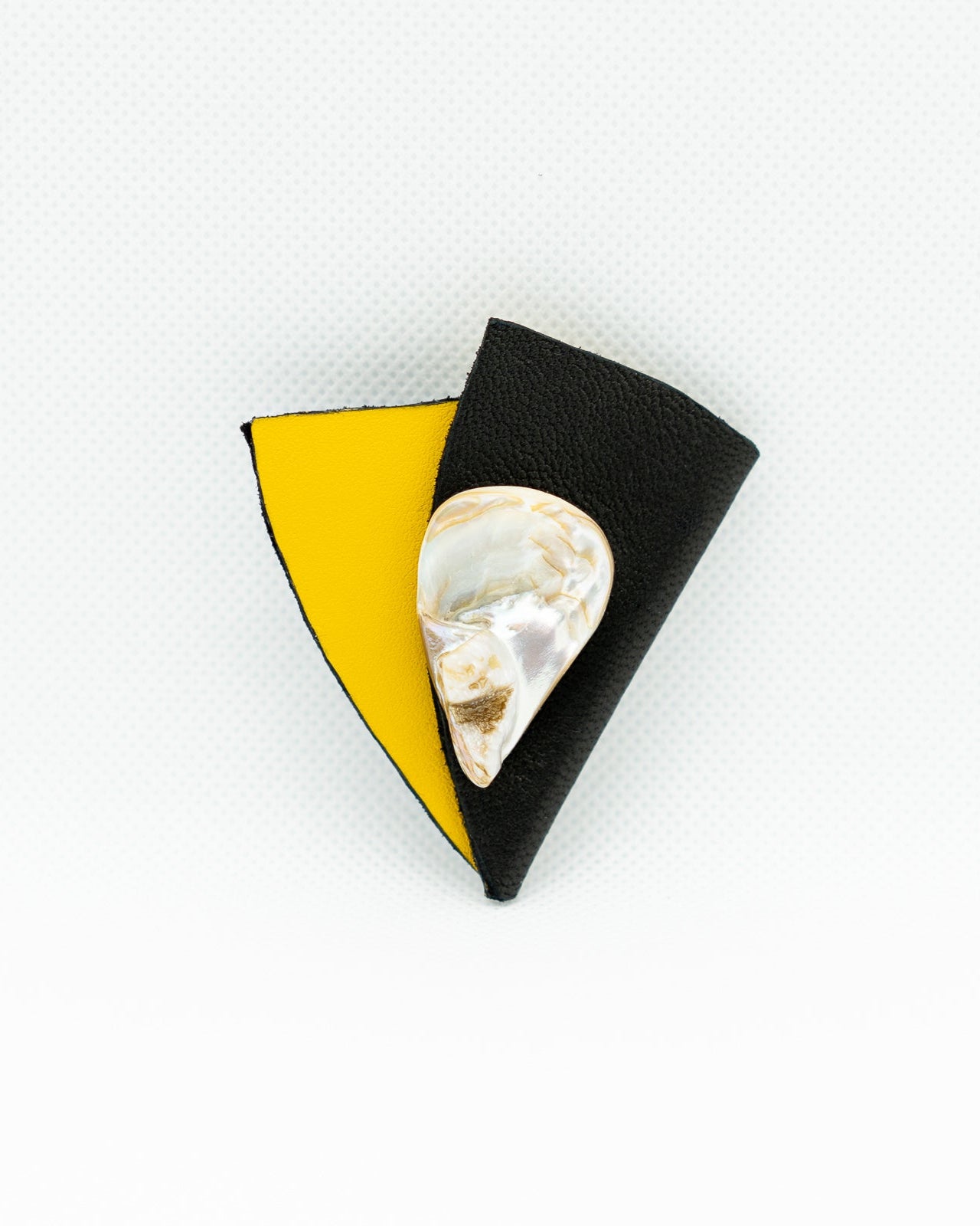 Brooch with a heart-shaped pearl on a black and yellow background