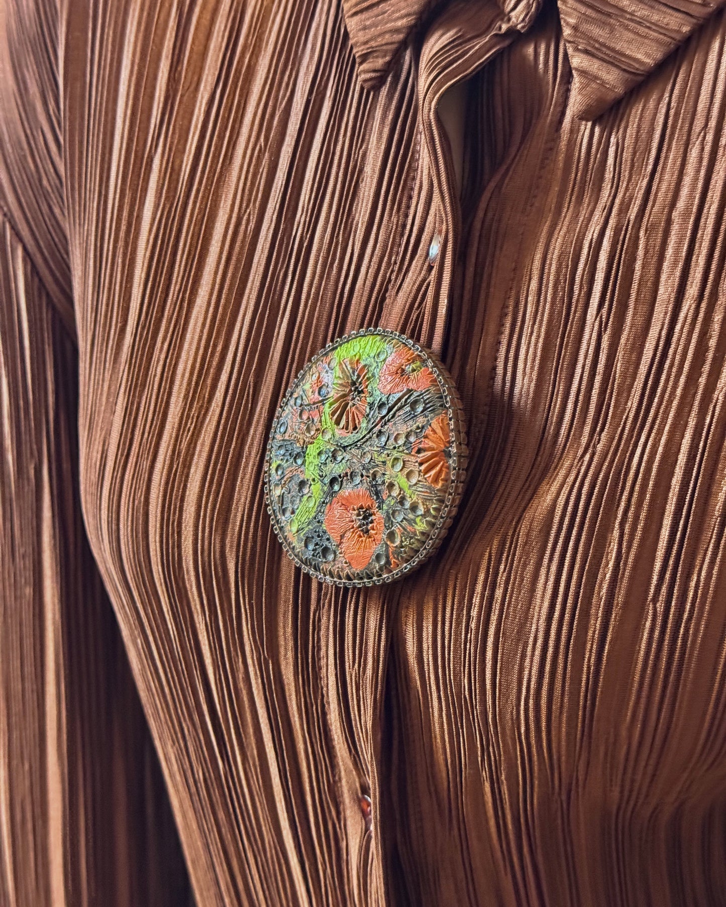 Decorative brooch with floral design on a brown textured fabric background