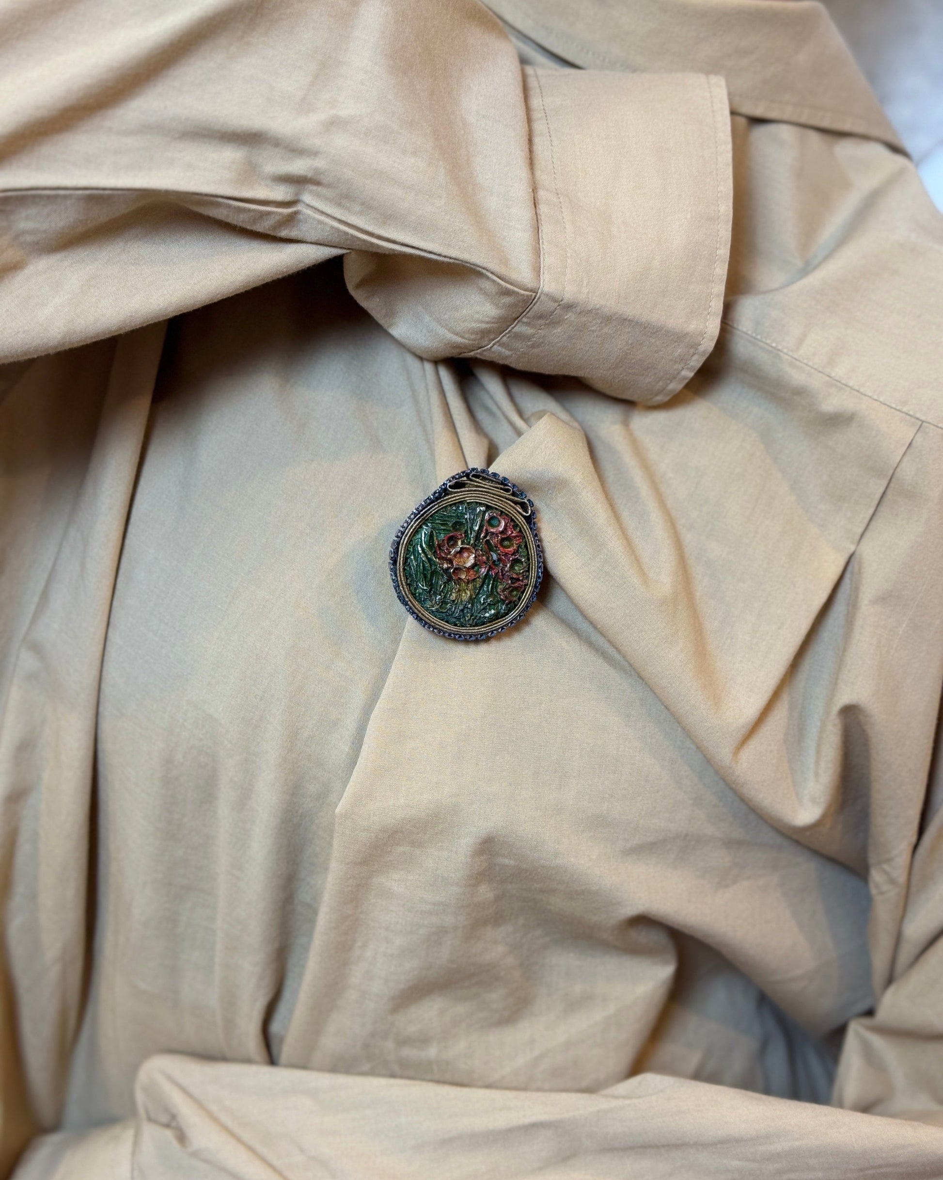 Close-up of a beige coat with a decorative button featuring a face design.