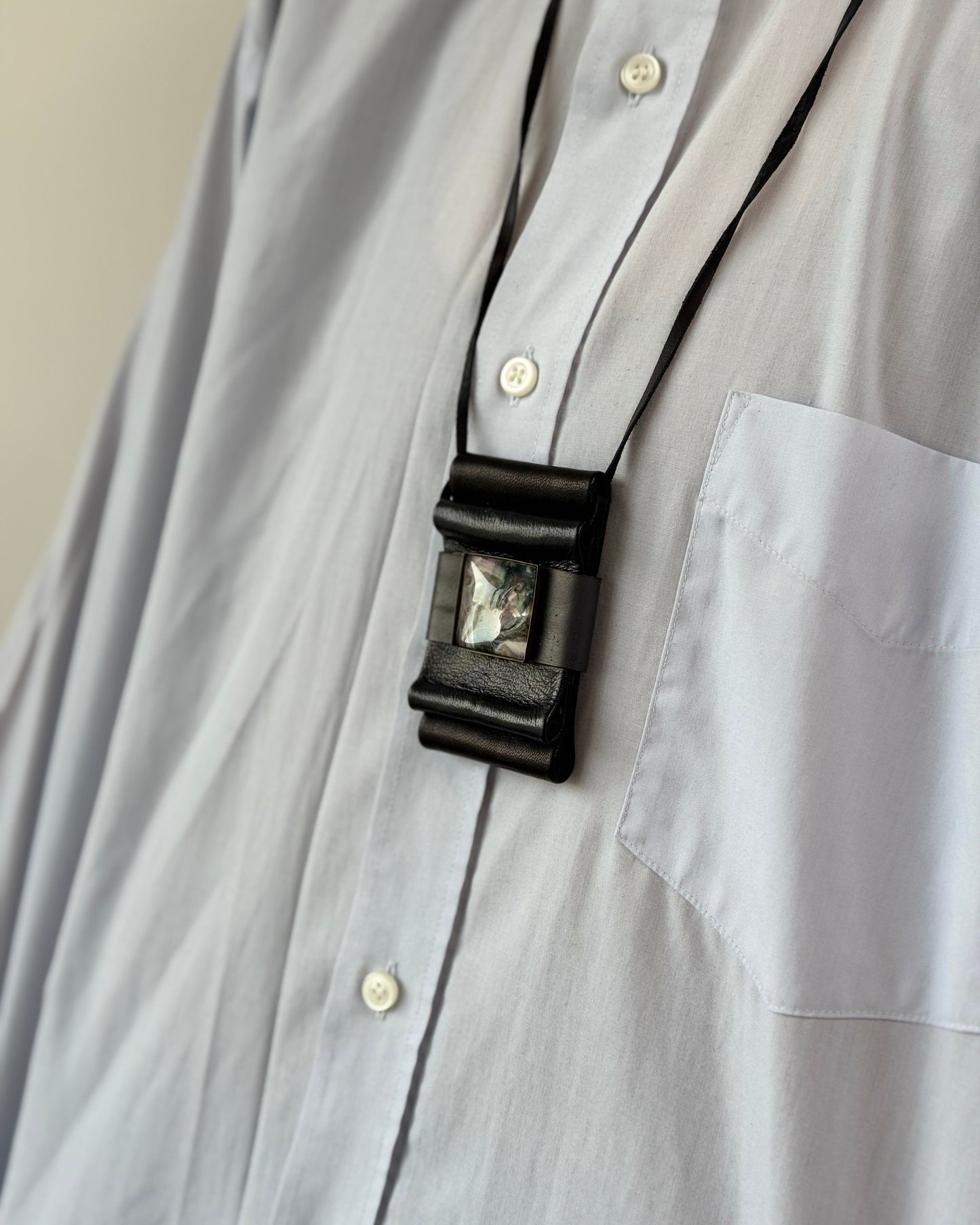 Close-up of a gray shirt with a black belt and decorative buckle.