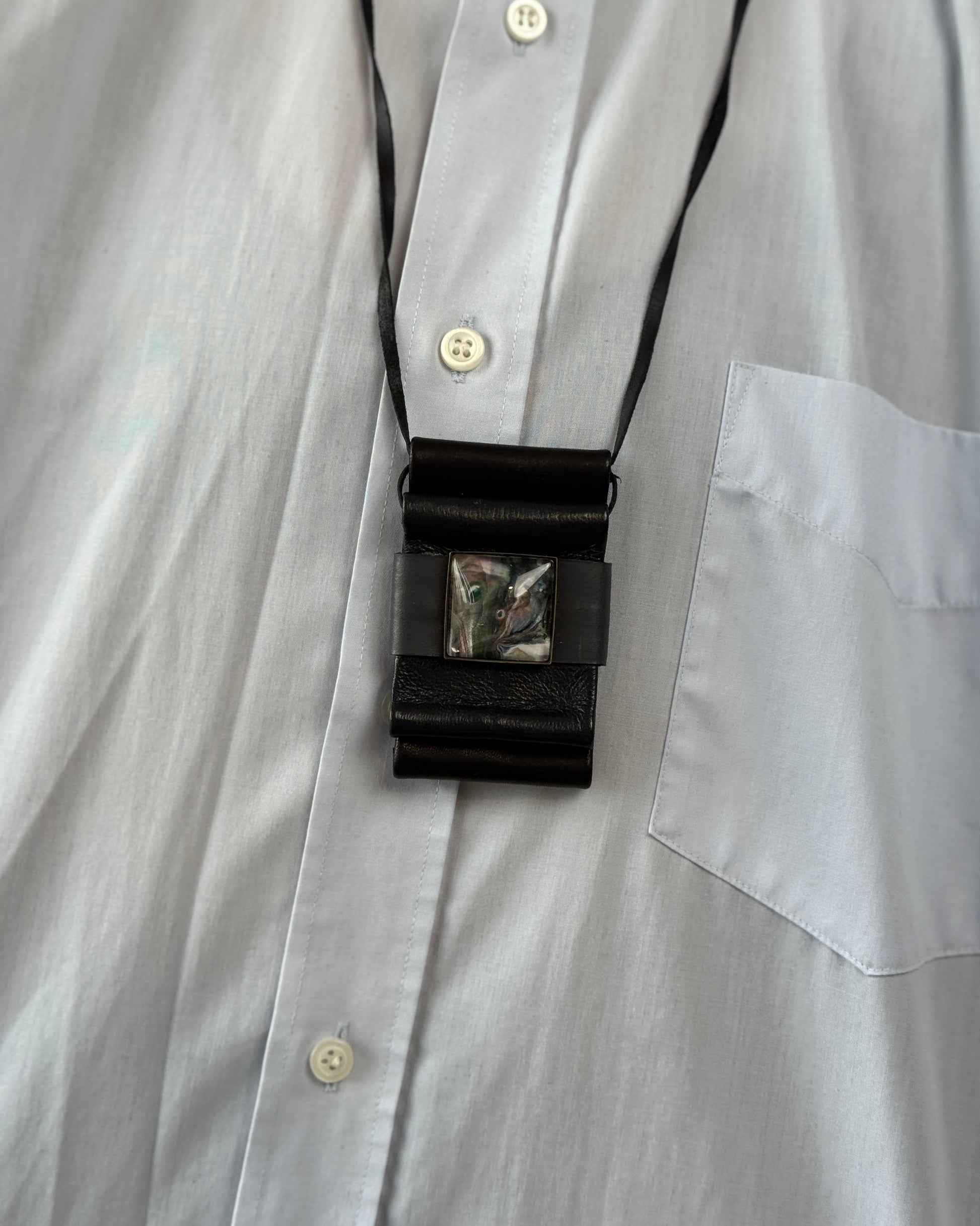 Black lanyard with a badge holder attached to a light gray shirt.