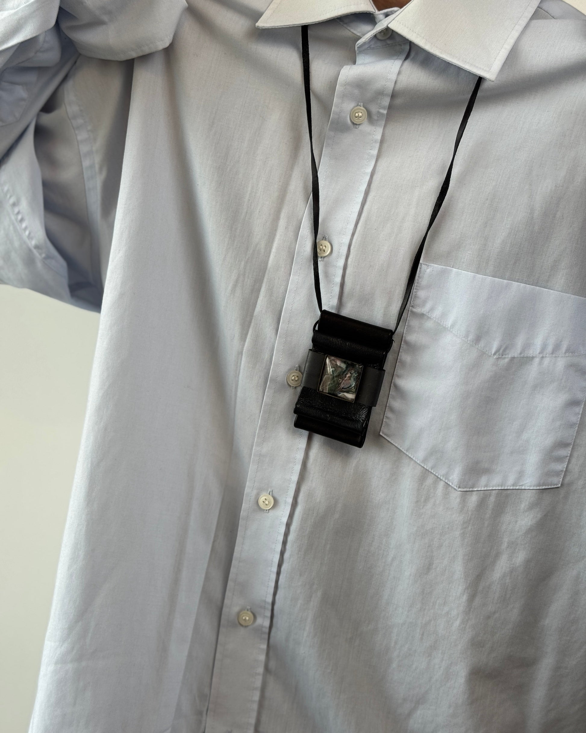 Light gray shirt with a black lanyard and badge holder on a white background
