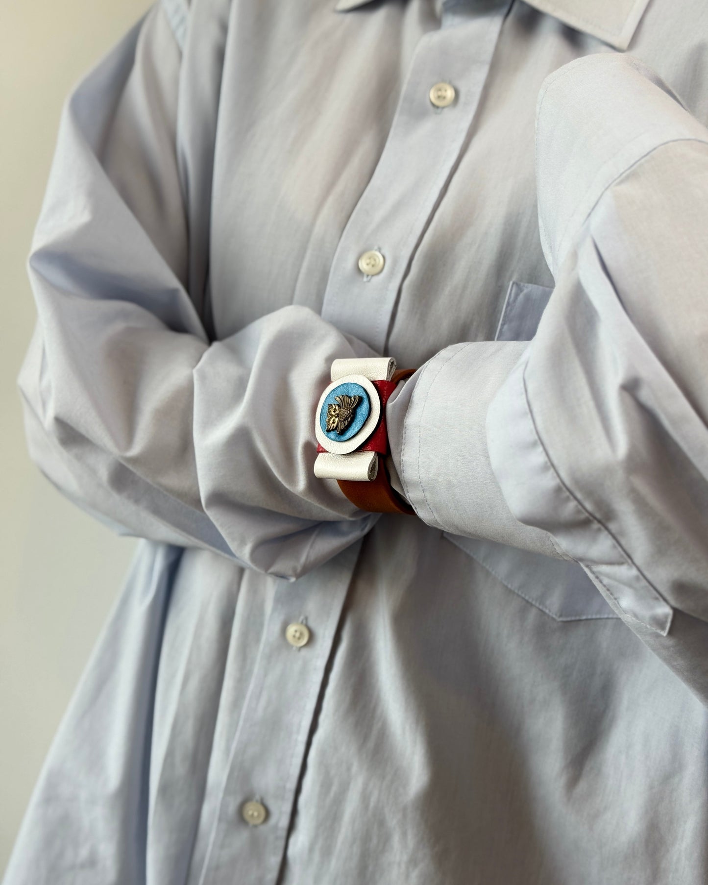 Light gray shirt with a decorative belt featuring a blue and gold buckle.