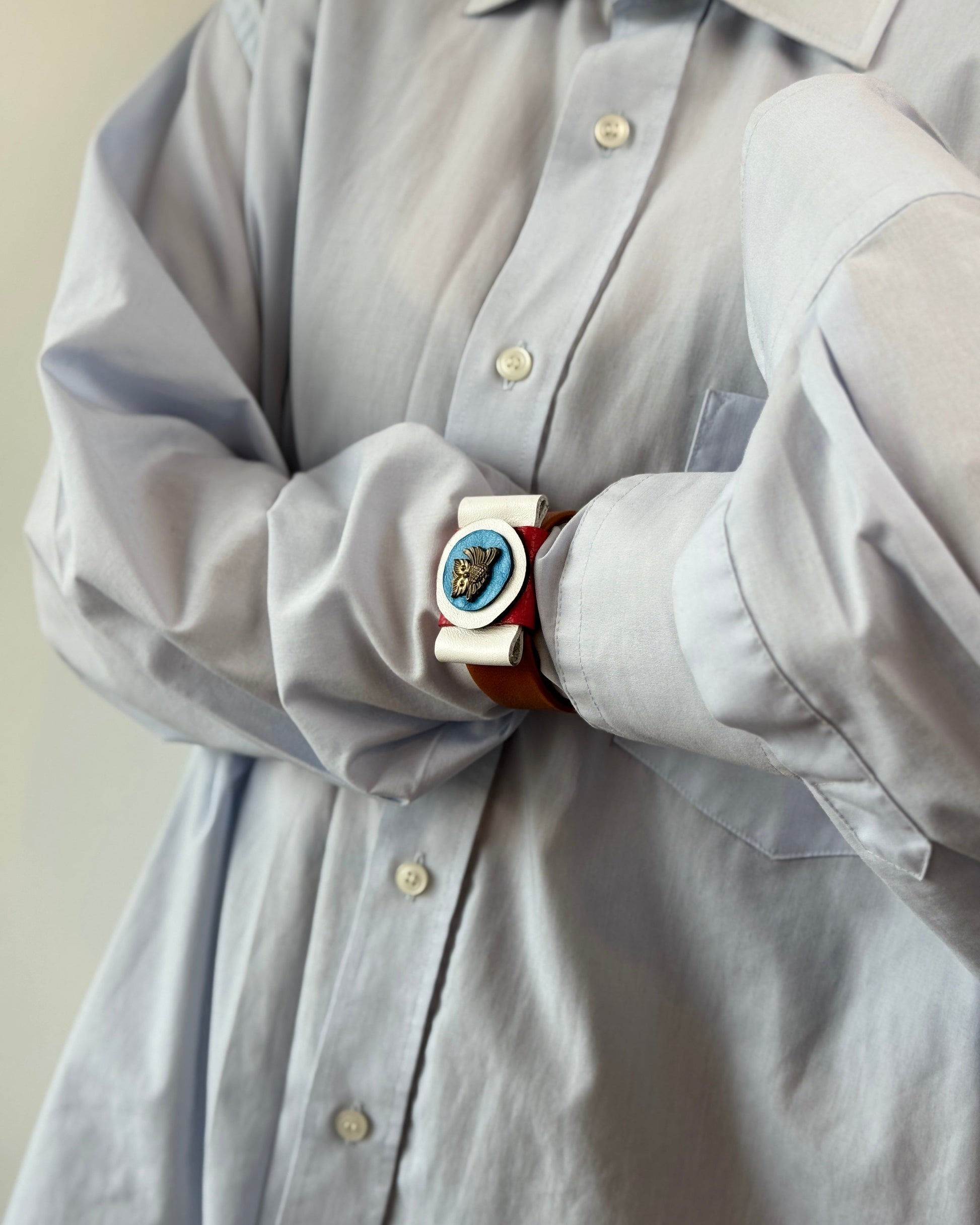 Light gray shirt with a decorative belt featuring a blue and gold buckle.