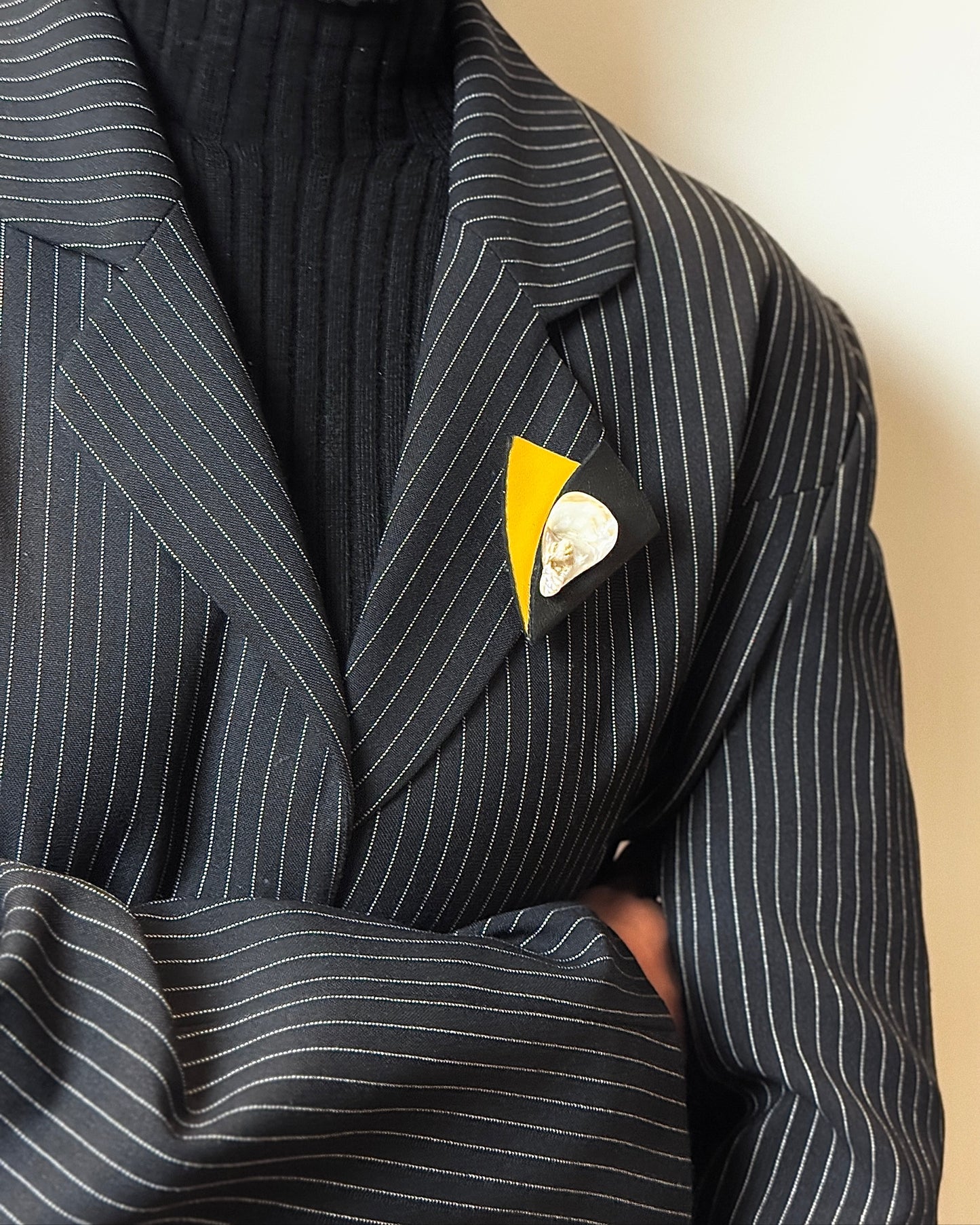 Person wearing a pinstripe suit with a decorative pocket square against a neutral background
